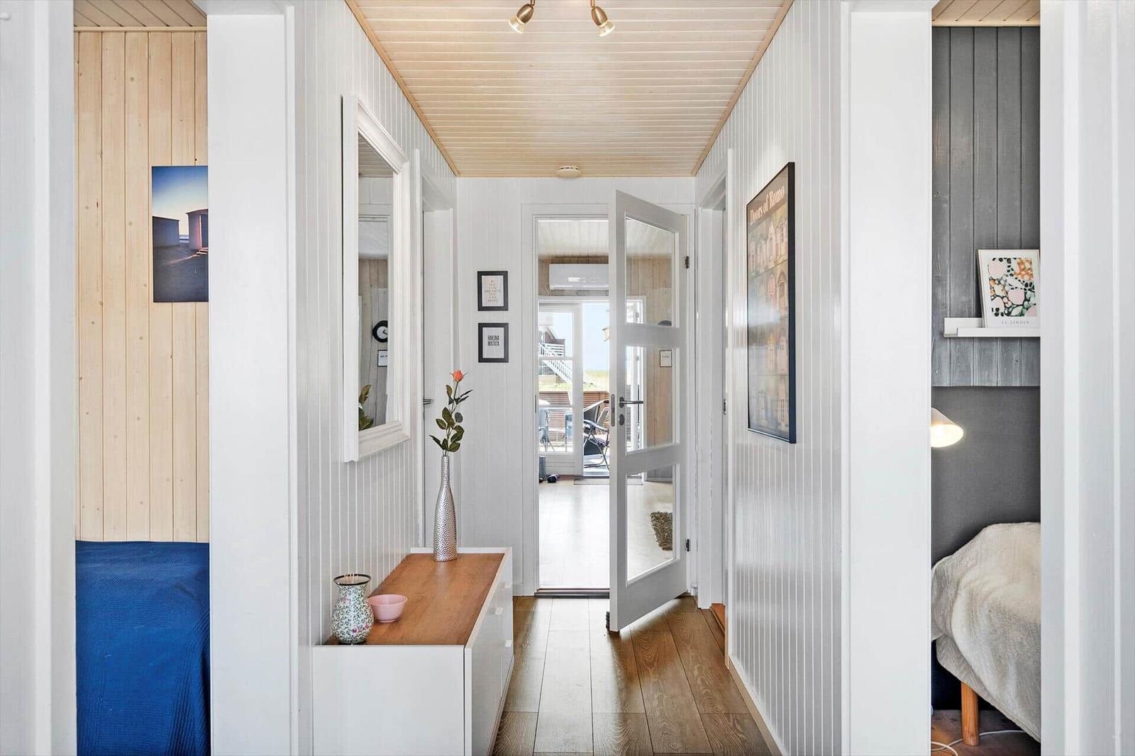 Hallway with wooden floor, white walls, and door to balcony. Bedrooms on left and right.