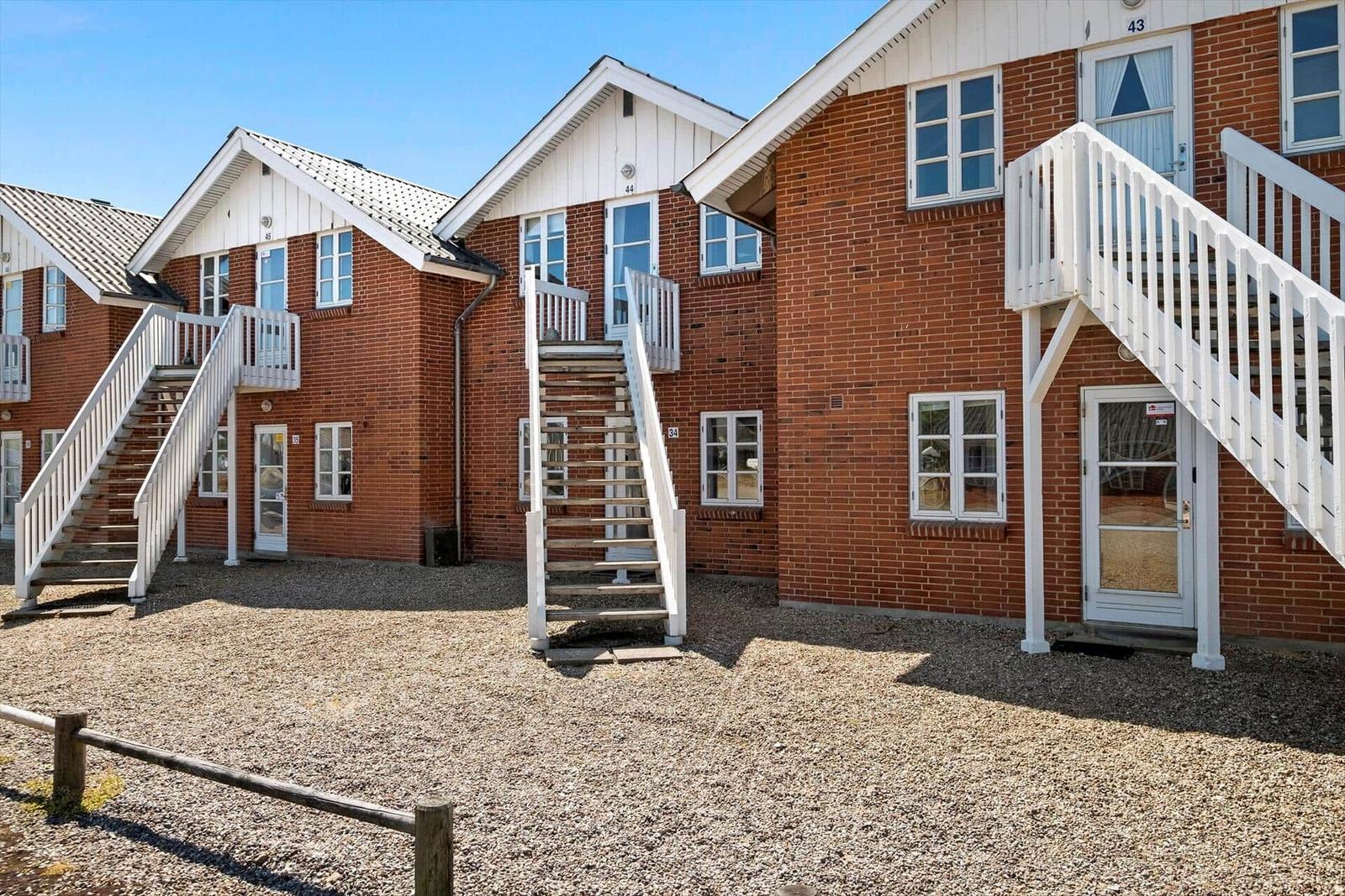 Red brick houses with white stairs and windows. Gravel ground and wooden railings.
