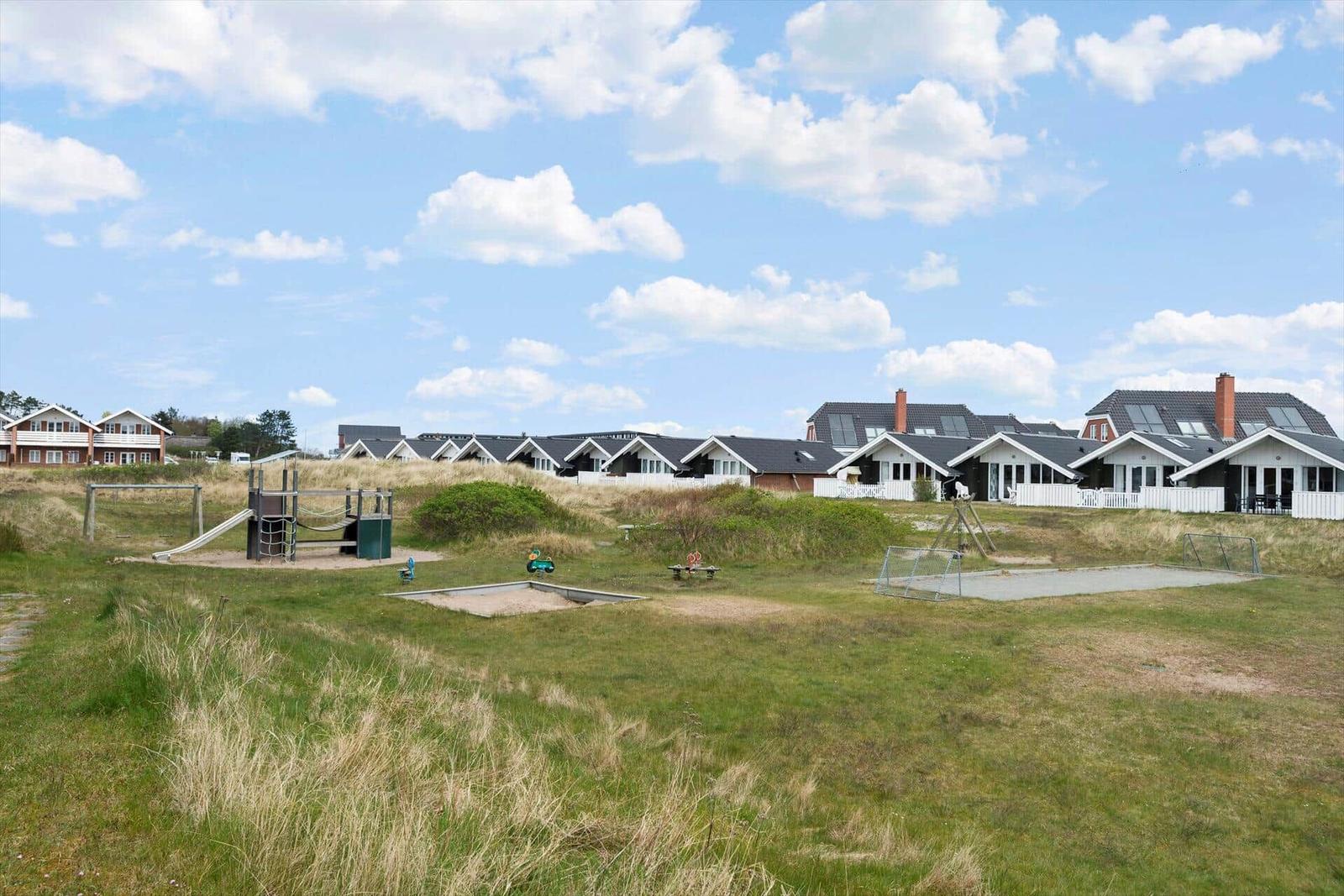 Green lawn with playground and vacation houses in the background.