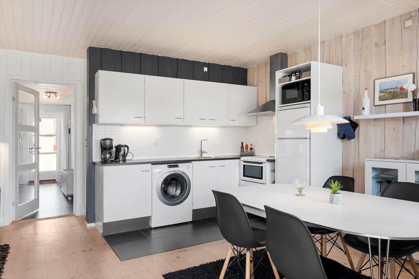 Kitchen with washing machine, dining area, and wooden wall
