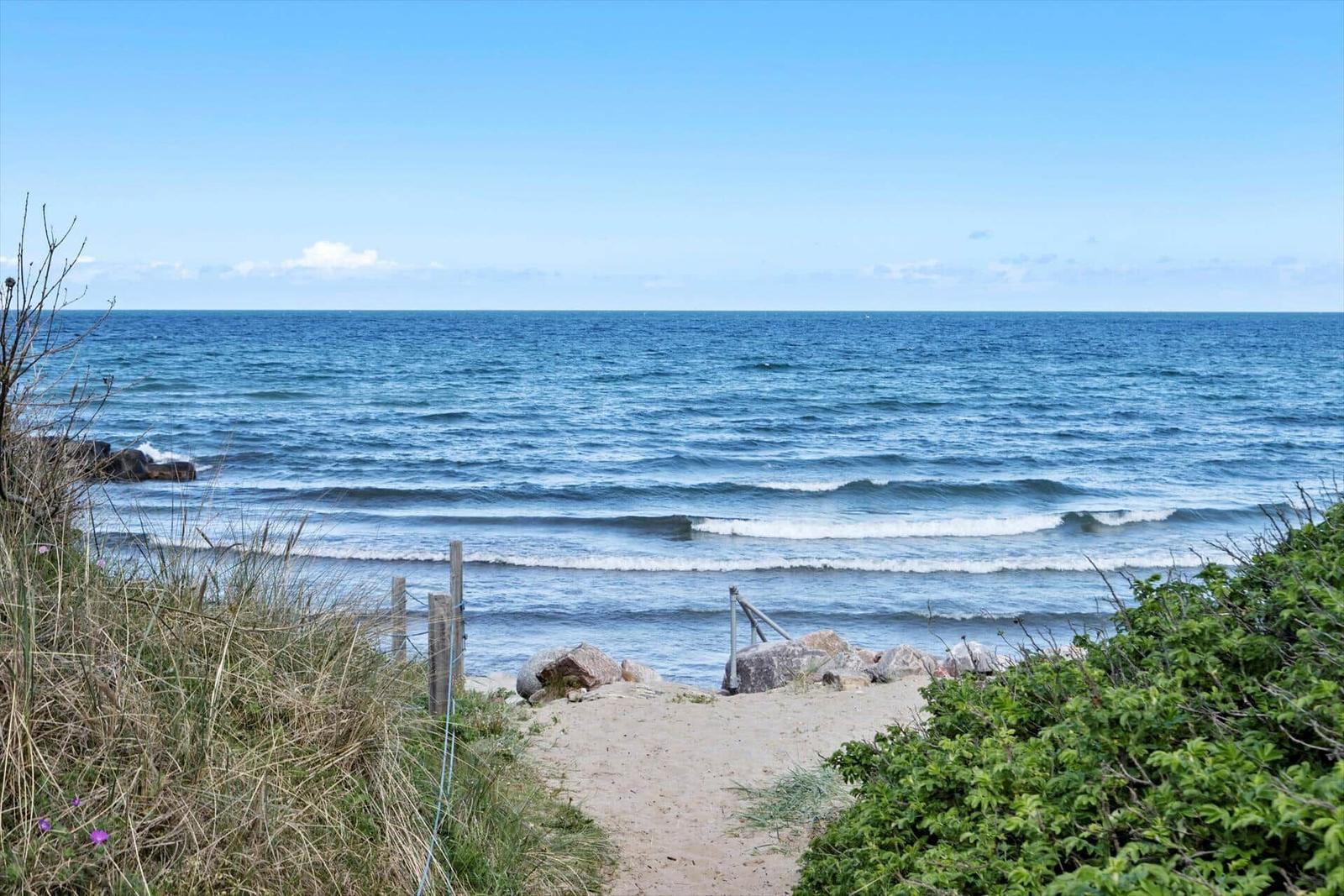 Sandweg führt zum Strand mit Blick auf das offene Meer.