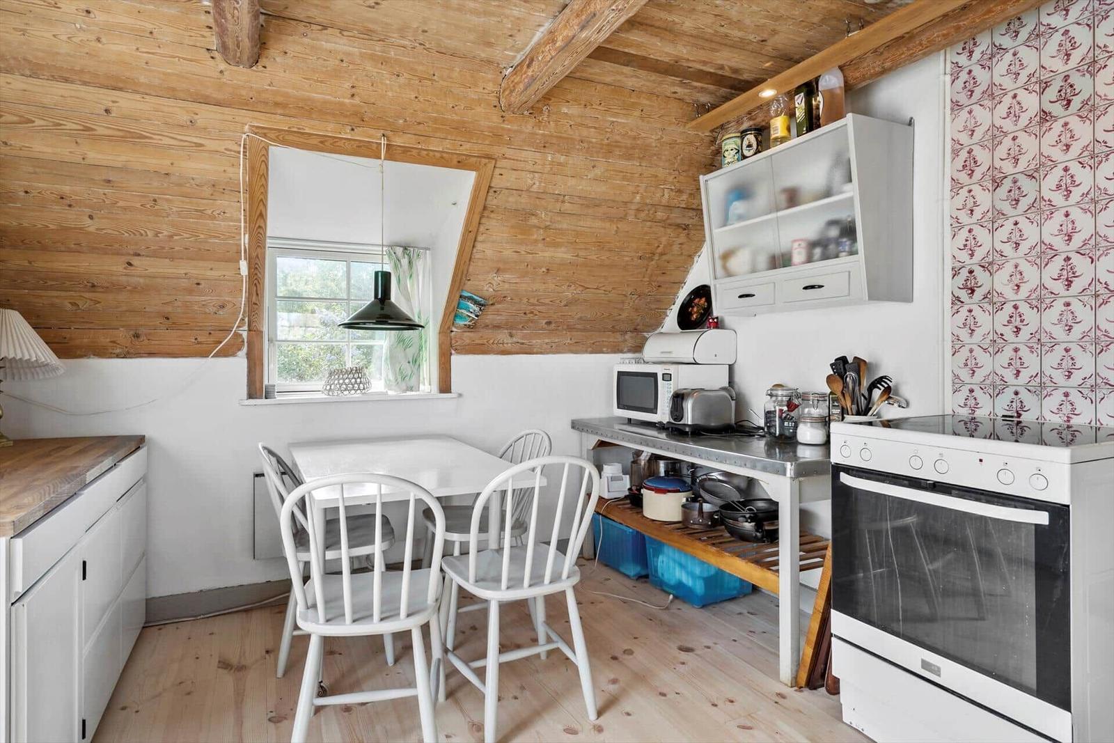 Küche mit Essbereich, Holzdecke und weißen Möbeln.