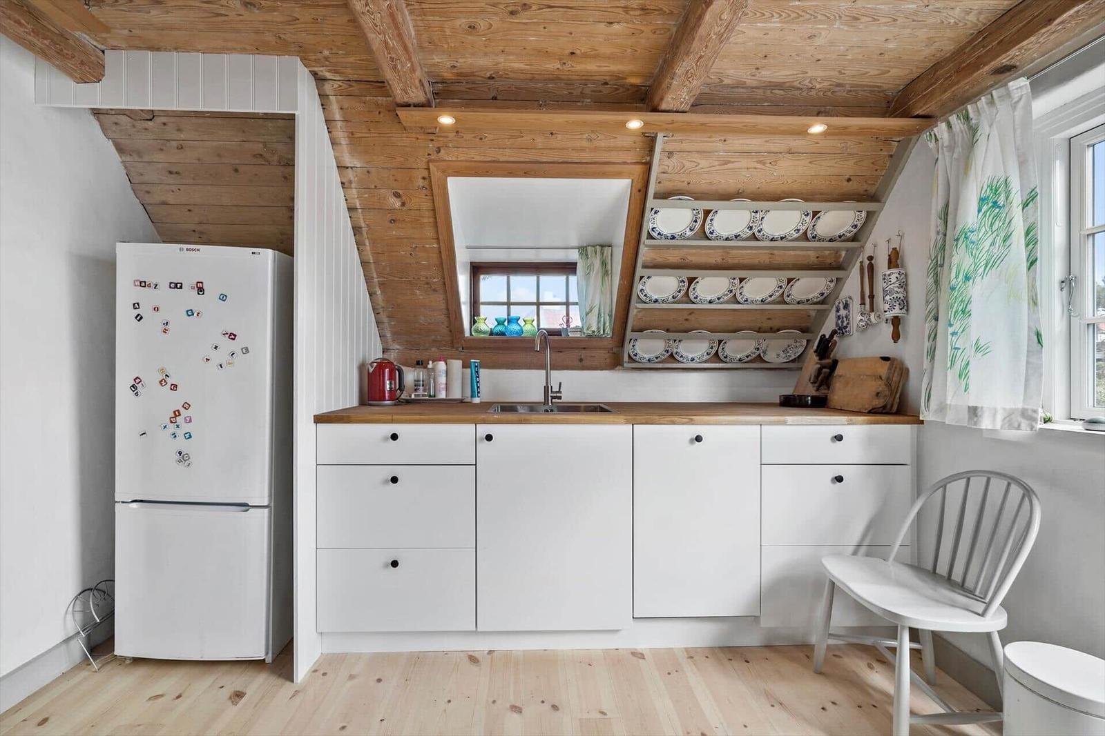 Küche mit weißer Arbeitsplatte, Holzdecke und Küchenzeile
