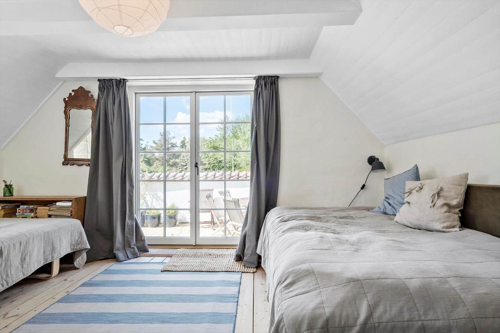 Schlafzimmer mit Dachschräge, Bett, Fenster und Holzboden.