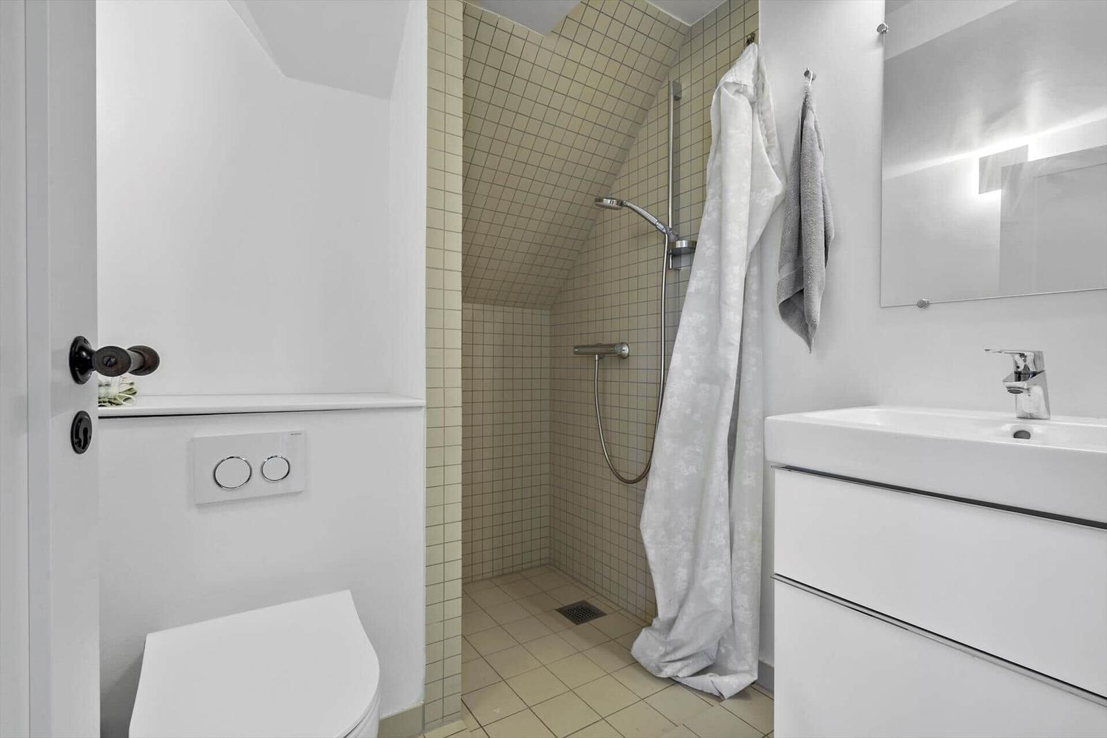 Badezimmer mit Dusche, Waschbecken und Toilette.