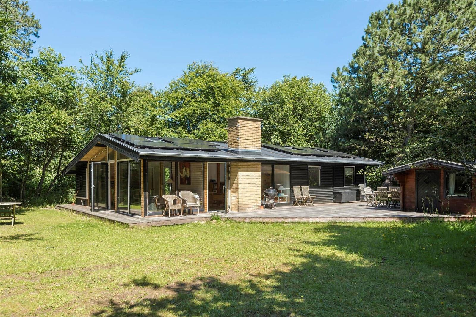 Moderne Villa mit Terrasse, Grill und Blick auf den Wald.