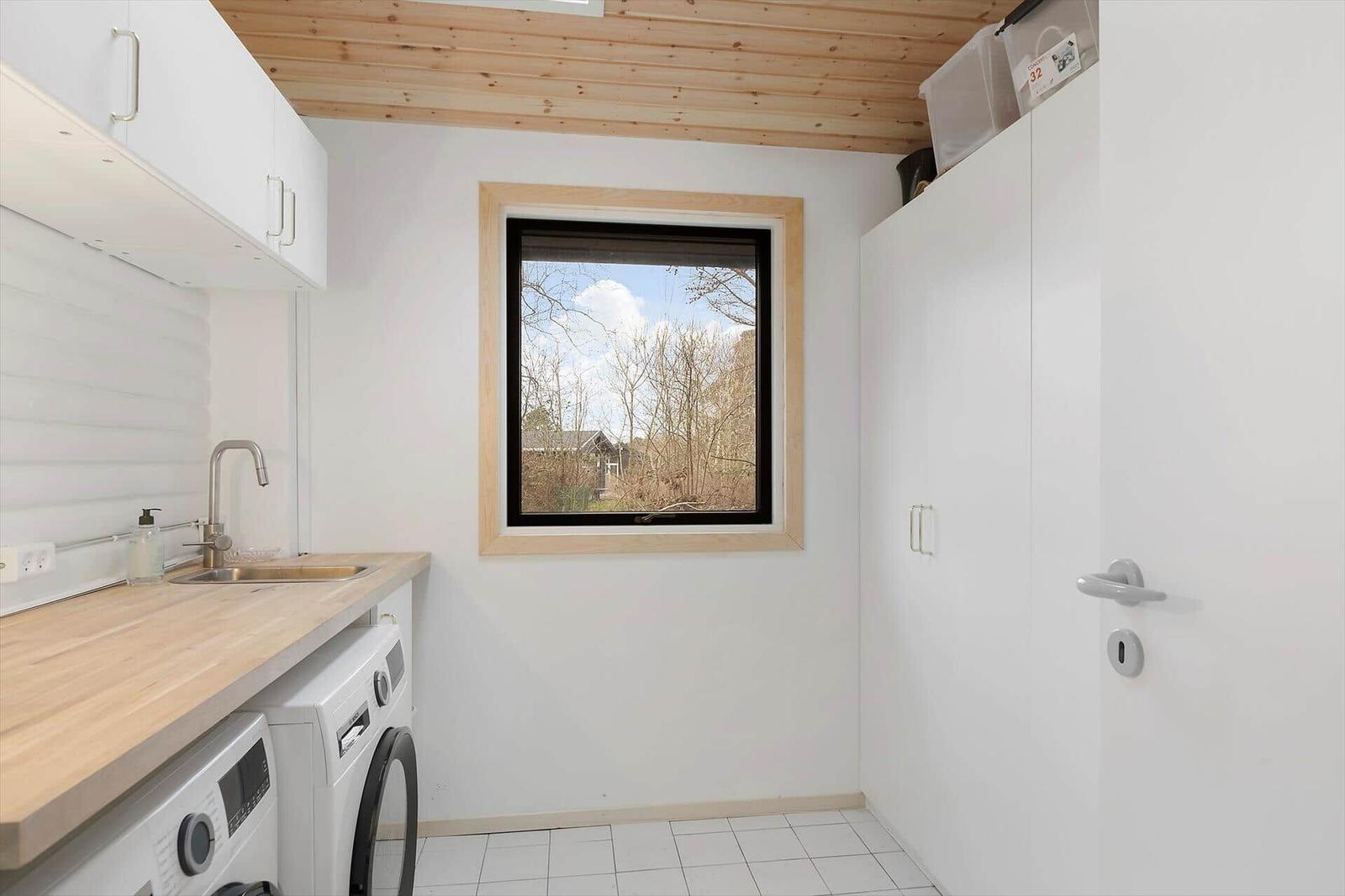 Küche mit Waschmaschine, Holzoberfläche und Fenster zur Aussicht.
