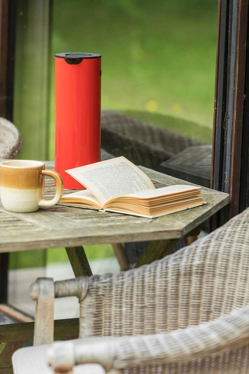 Auf dem Balkon steht ein Tisch mit Buch, Tasse und rotem Thermobecher.