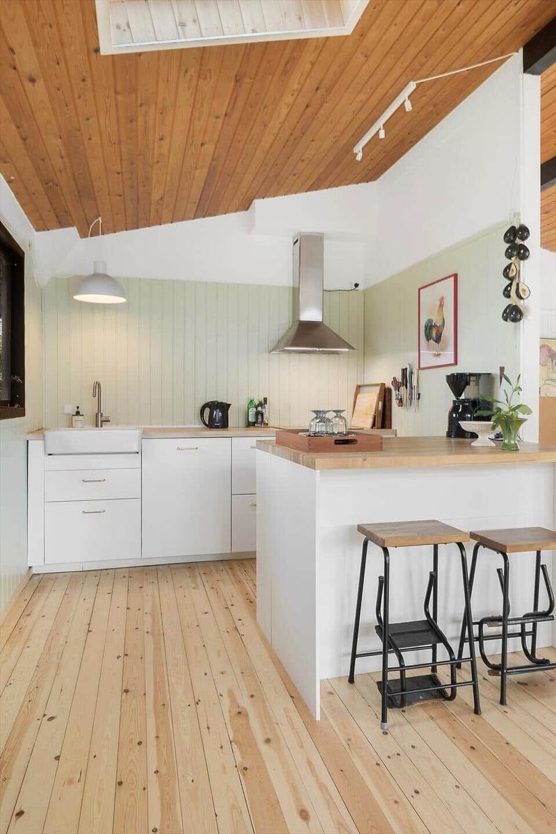 Küche mit Holzdecke, weißen Schränken und Holzwerkzeugen an der Wand.
