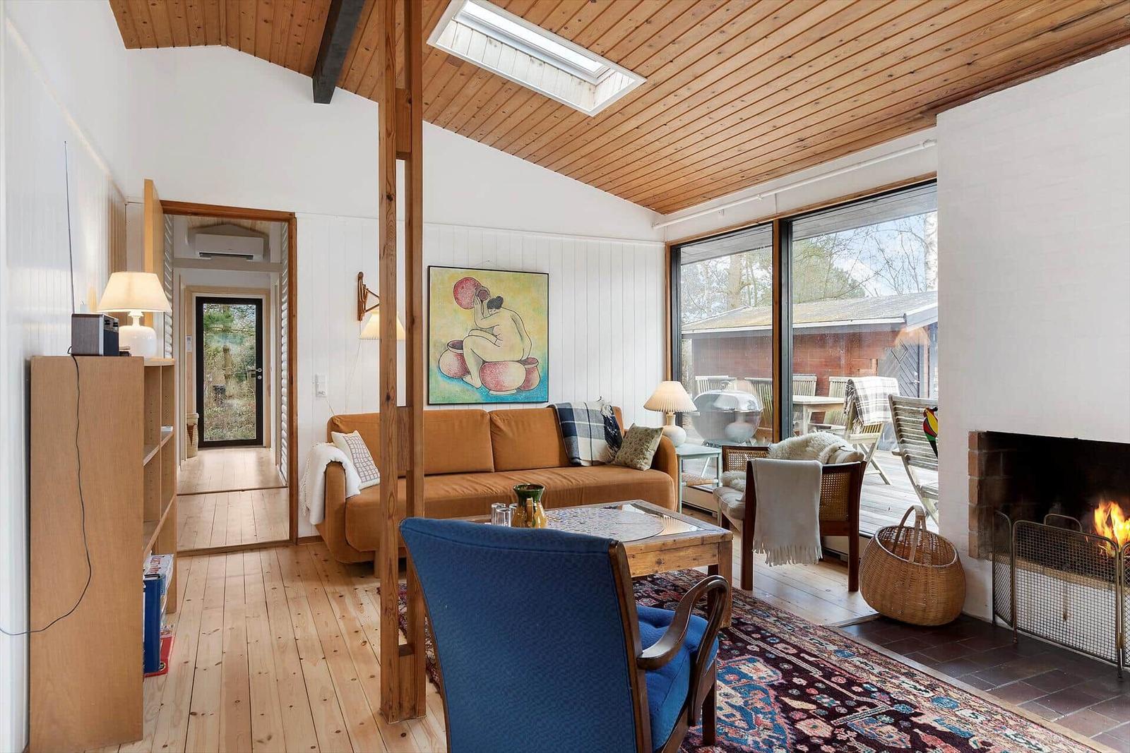 Wohnzimmer mit Kamin, Sofa und Glasfront zum Garten