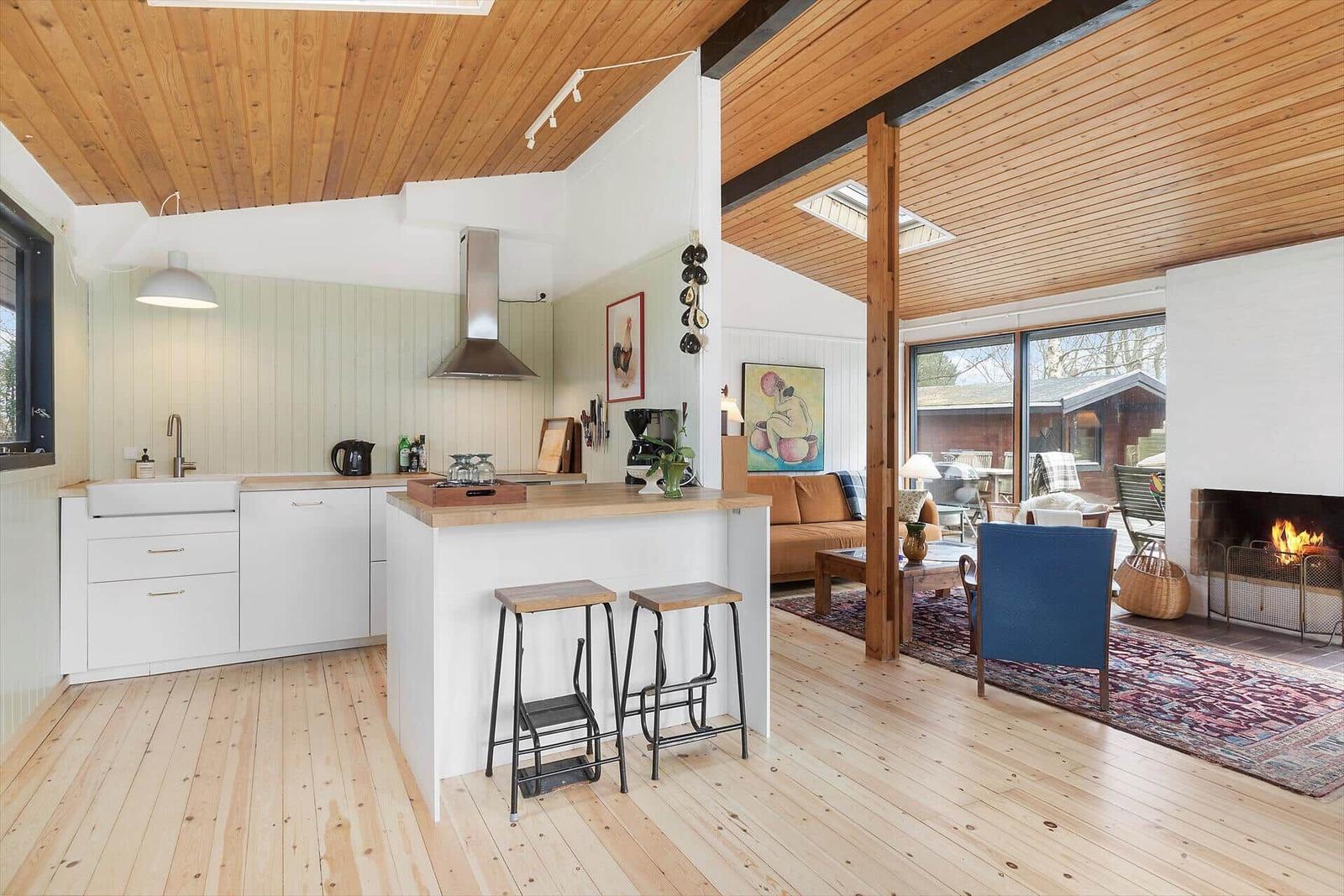 Küche mit Insel und Wohnzimmer mit Kamin und Holzboden