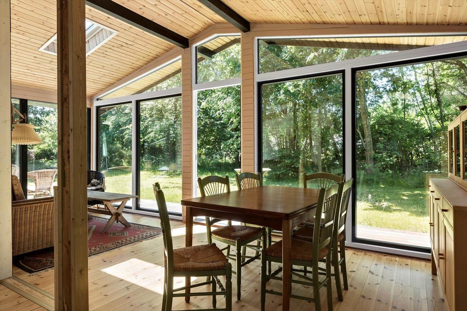 Esszimmer mit Holztisch, Stühlen und großen Fenstern zum Garten