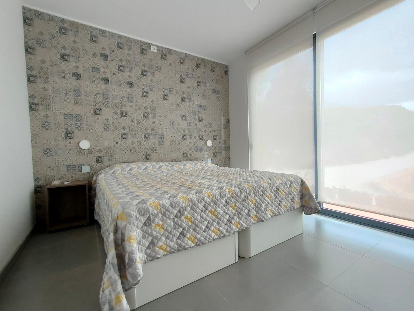 Schlafzimmer mit Bett, Tapete und großem Fenster.
