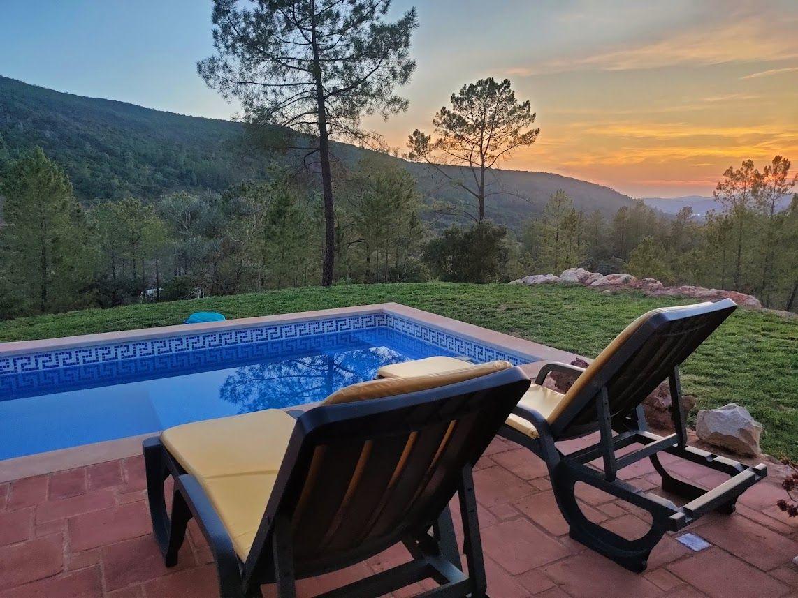 Pool mit Liegestühlen und Bergblick bei Sonnenuntergang.