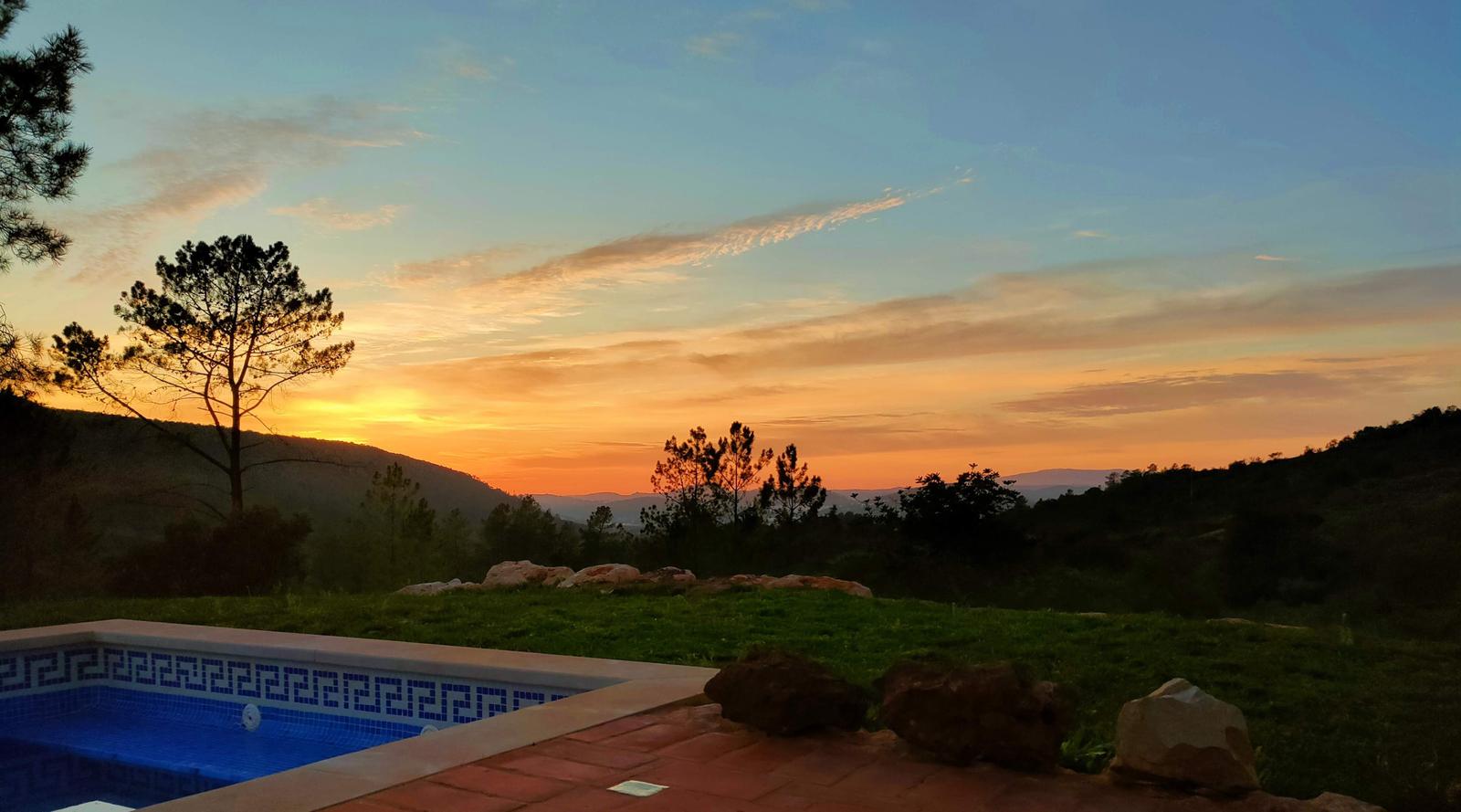 Pool mit Blick auf Sonnenuntergang über Hügeln und Bäumen