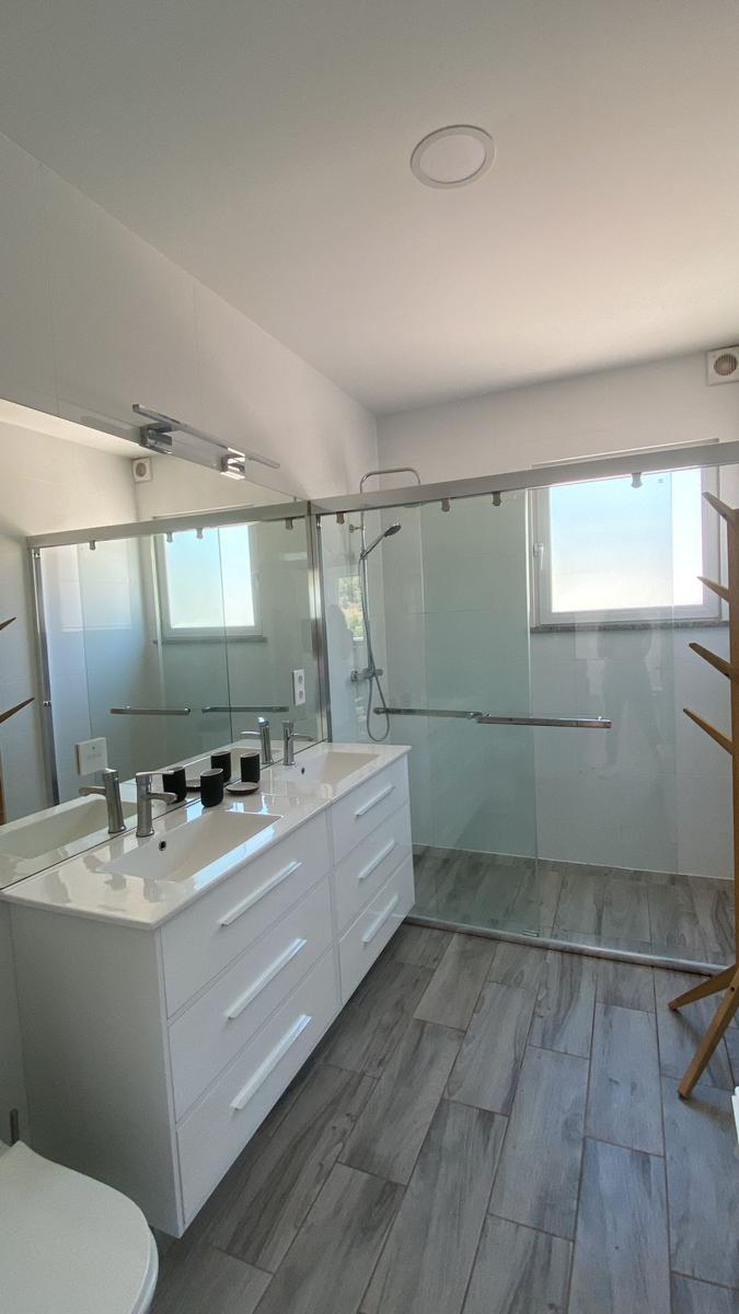 Badezimmer mit Dusche, Waschbecken und Spiegel.