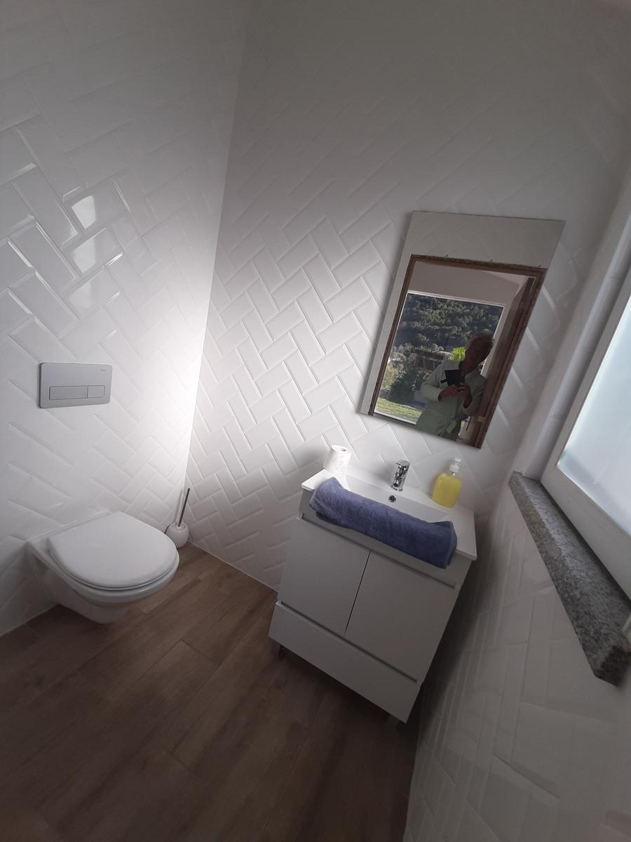 Badezimmer mit Toilette, Waschbecken und Spiegel an der Wand.