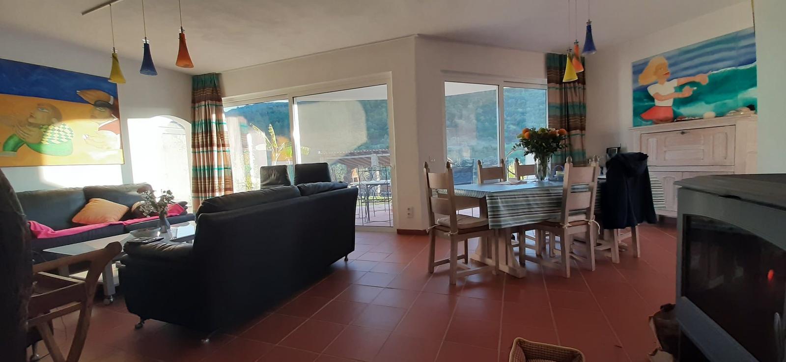 Wohn- und Essbereich mit Sofa, Tisch und Blick auf Balkon.