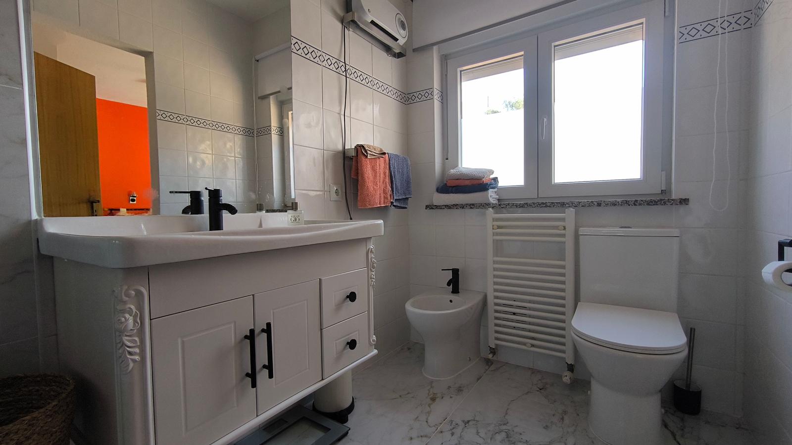 Badezimmer mit Waschbecken, Toilette, Bidet und Fenster.