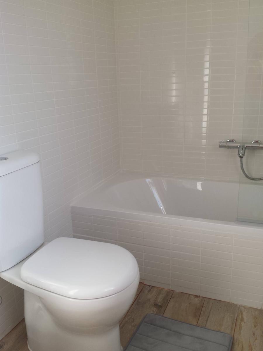 Badezimmer mit Badewanne, Toilette und Fliesenwand