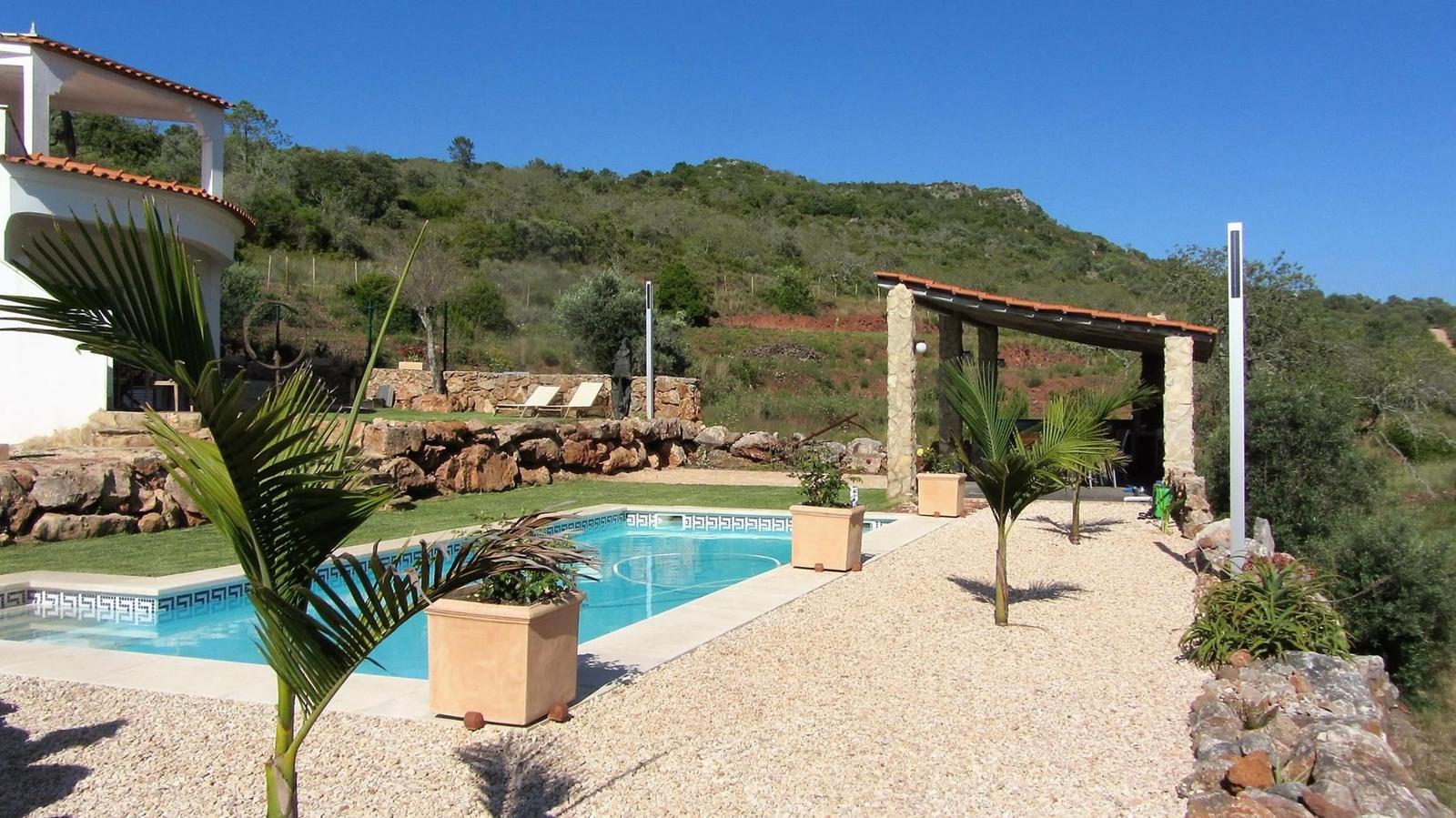 Pool mit Liegestühlen, Terrasse und Blick auf Hügel