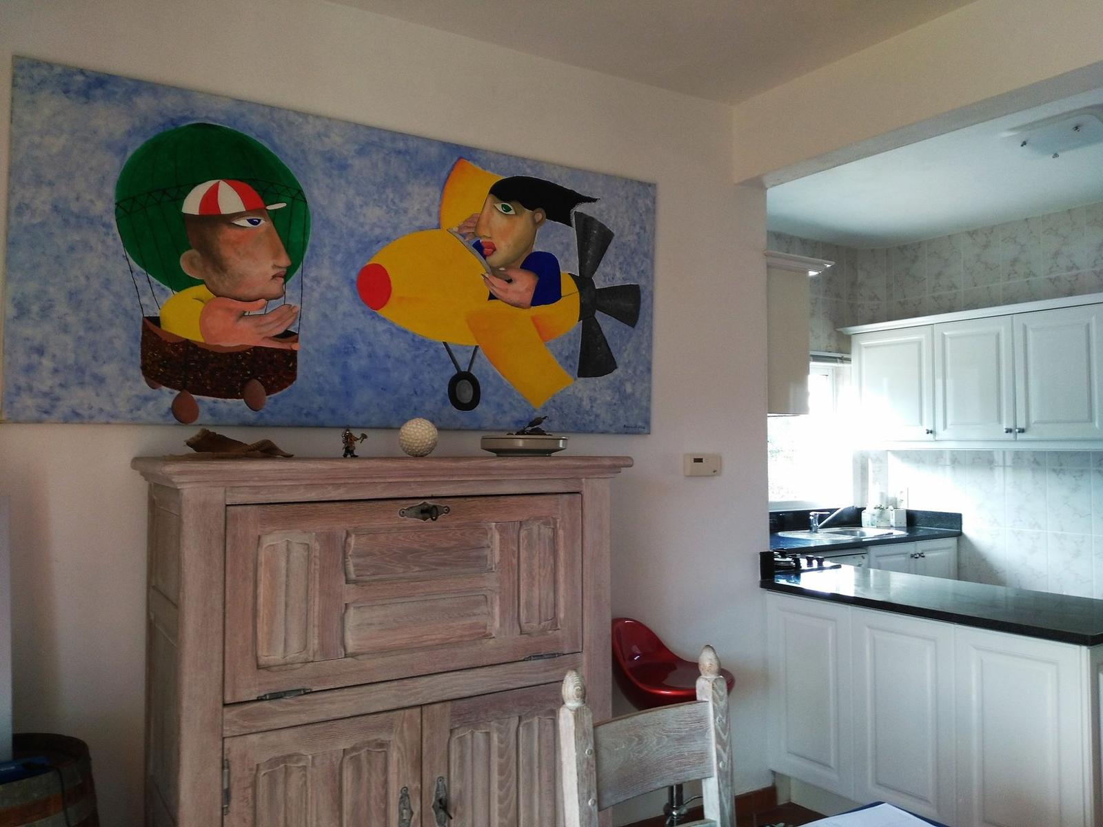 Großes Wandbild über Holzschrank, Küche mit weißen Schränken und schwarzer Arbeitsplatte.