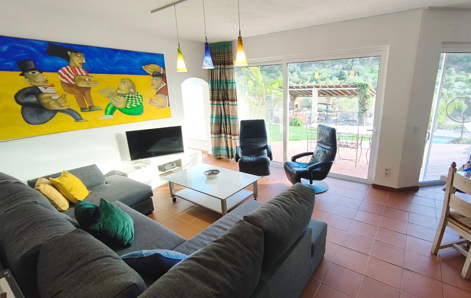 Wohnzimmer mit Sofa, Fernseher und Blick auf Terrasse