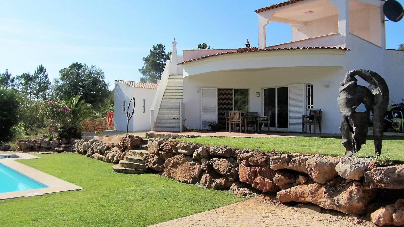 Eine Villa mit Pool, Terrasse und Steinmauer im Garten.