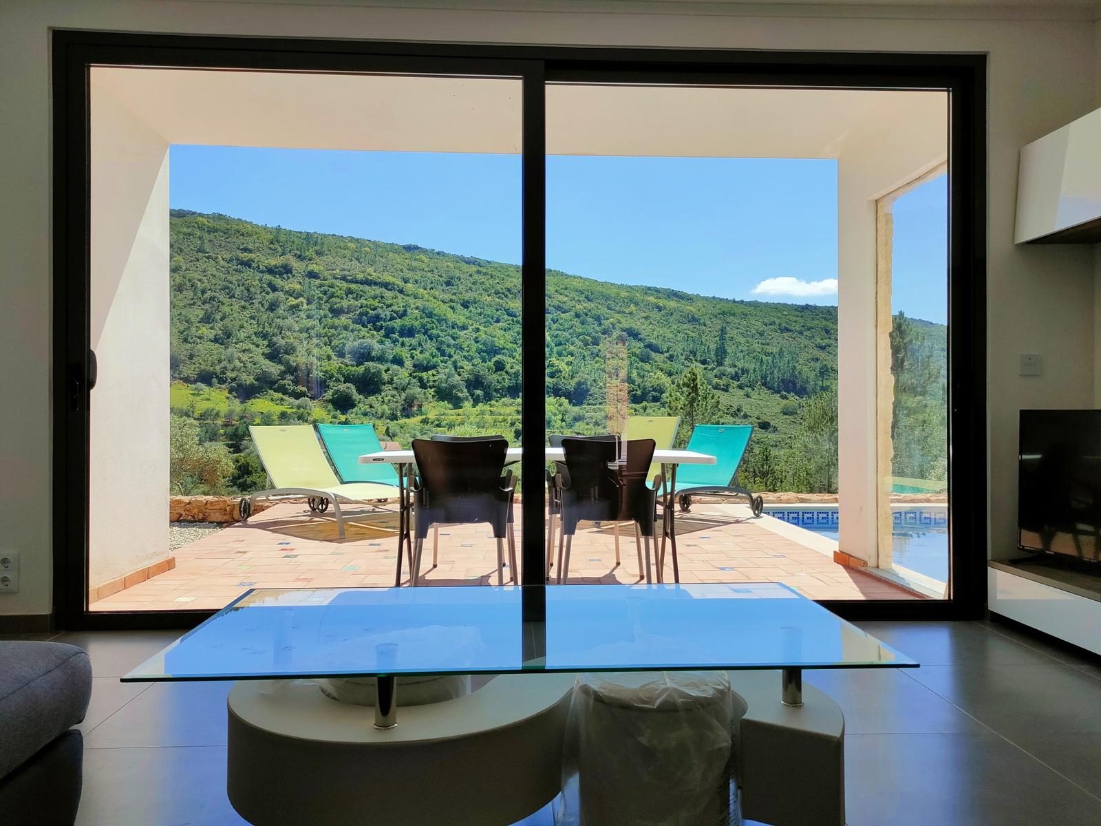 Terrasse mit Pool und Bergblick durch große Glastüren