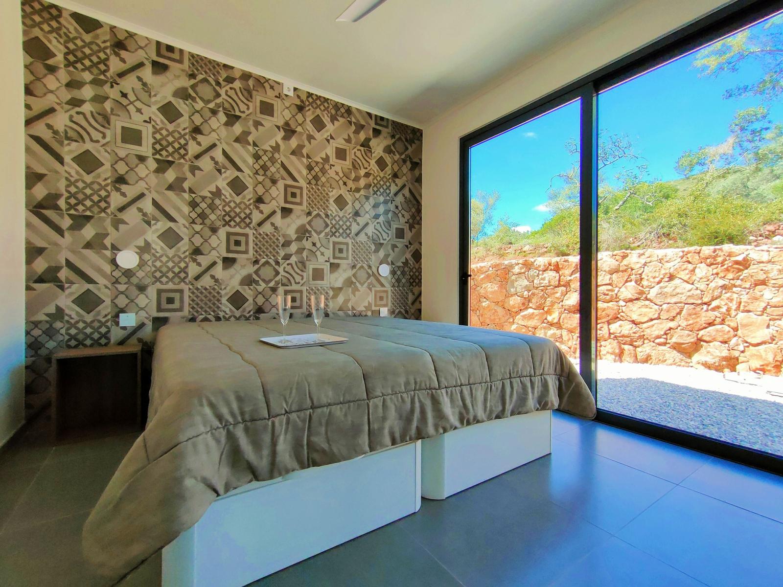 Schlafzimmer mit gemusterter Wand und Blick auf Steinmauer