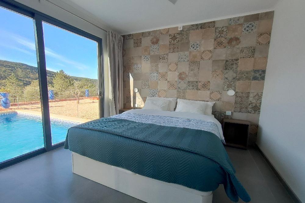 Schlafzimmer mit Blick auf Pool und Landschaft.