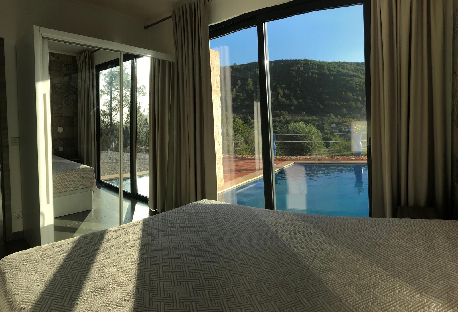 Schlafzimmer mit Blick auf Pool und Berglandschaft.