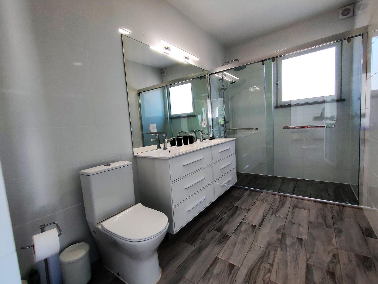 Badezimmer mit Dusche, Waschbecken und Toilette.