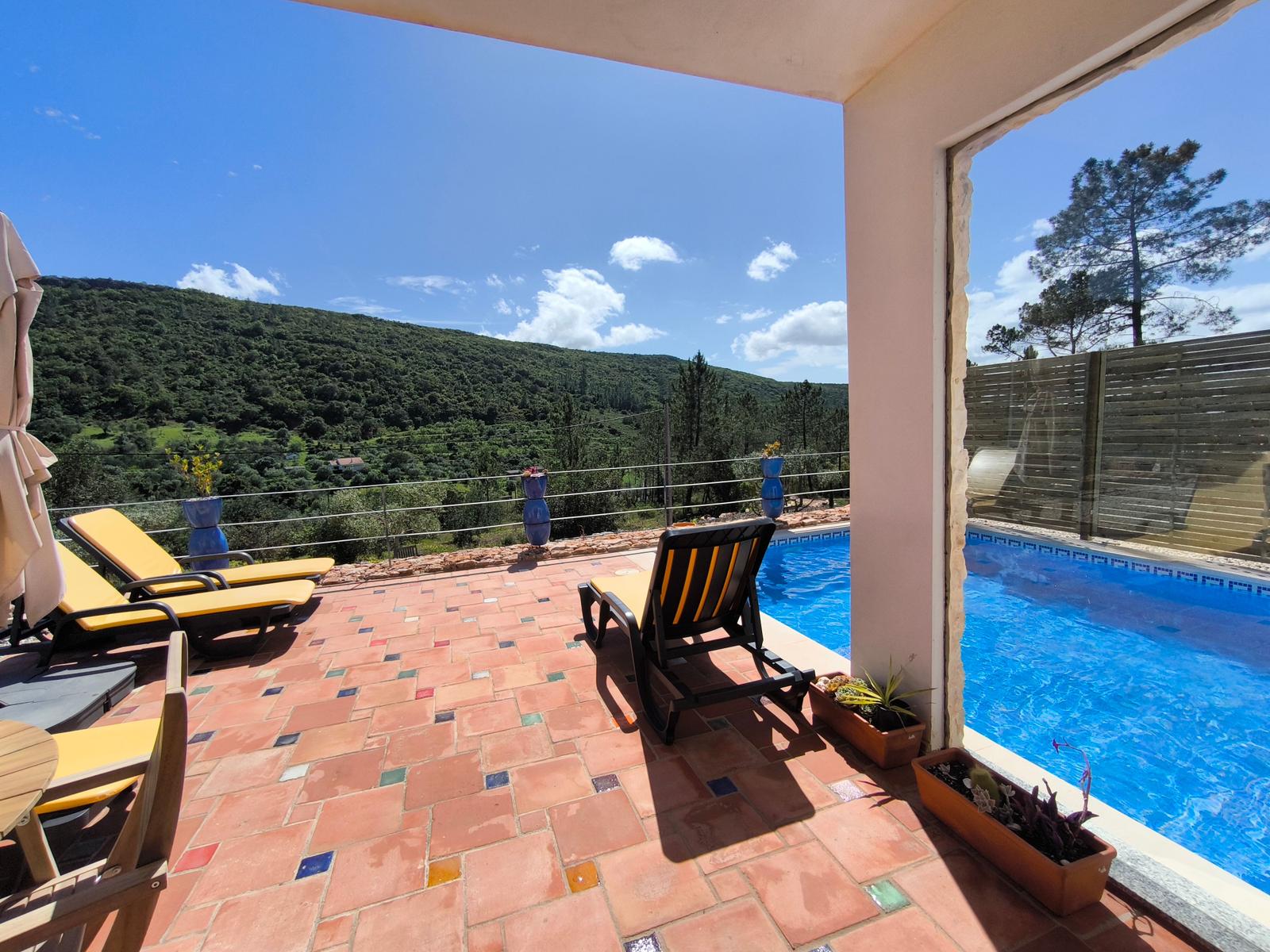 Terrasse mit Pool, Sonnenliegen und Bergblick.