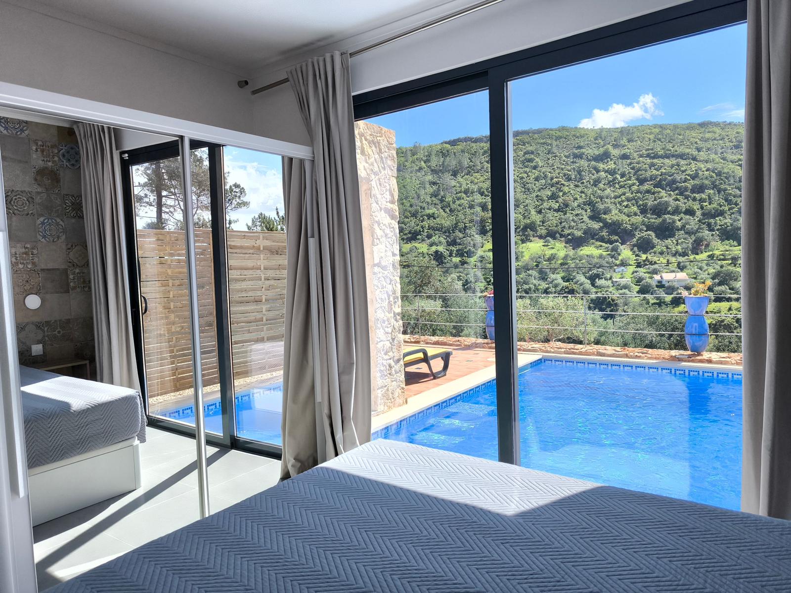 Zimmer mit Blick auf Pool und grüne Hügel