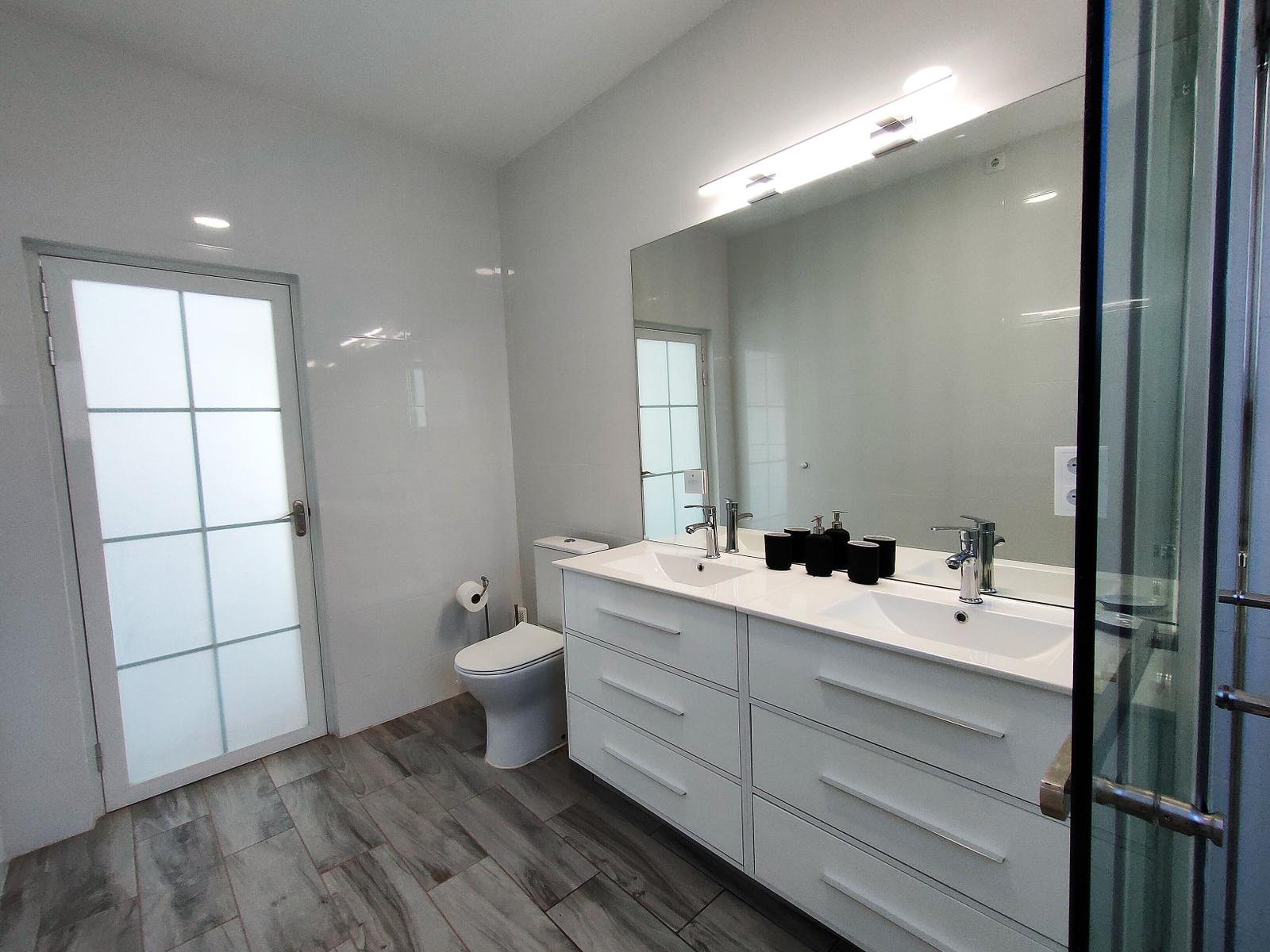 Badezimmer mit Doppelwaschbecken, Spiegel und Dusche.