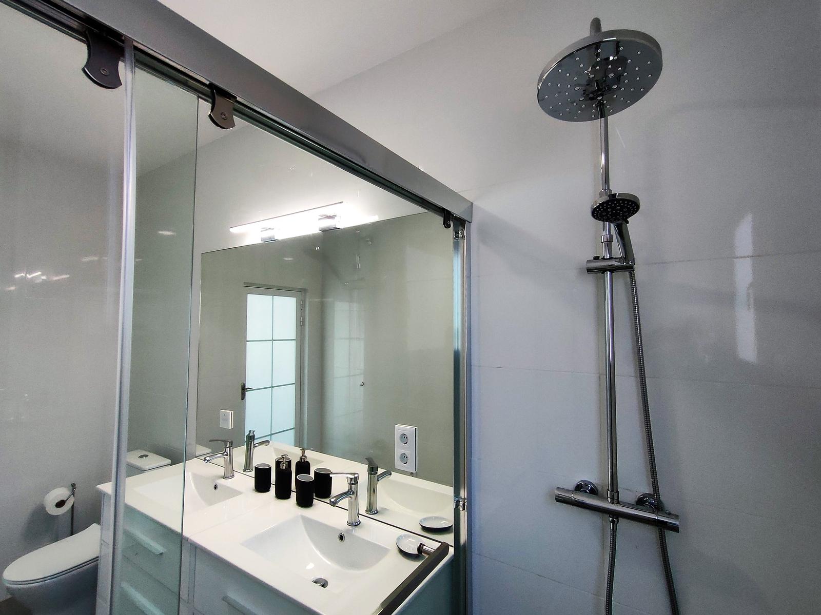Badezimmer mit Dusche, Waschbecken und Toilette.