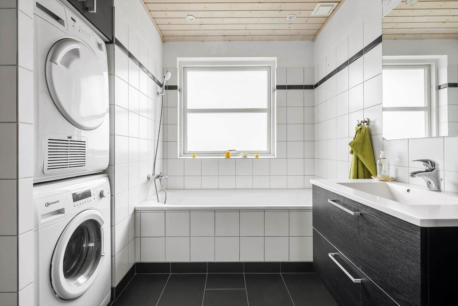 Badezimmer mit Badewanne, Waschmaschine und Spiegel