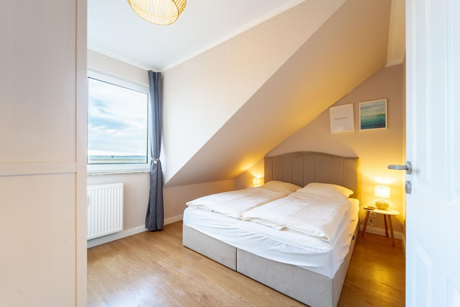 Schlafzimmer mit Dachschrägen, Bett, Fenster und Nachttisch