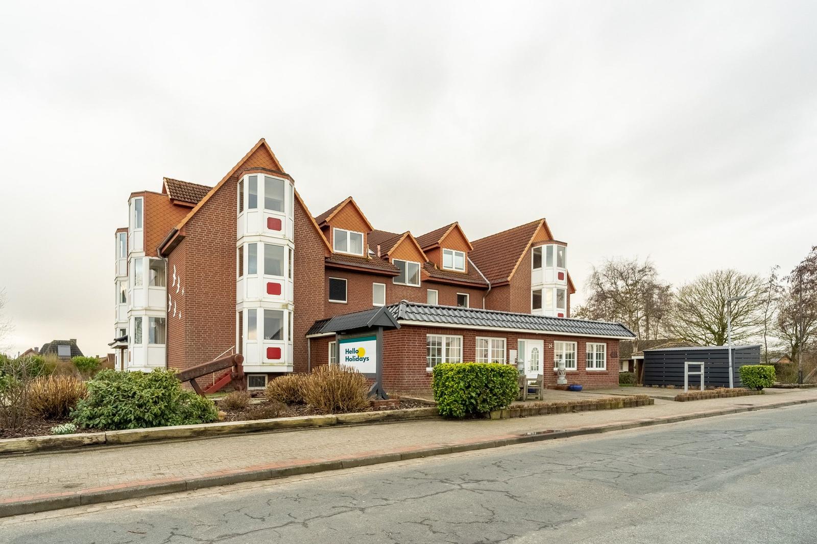 Rotes Backsteinhaus mit weißen Balkonen und Dachgauben an der Straße