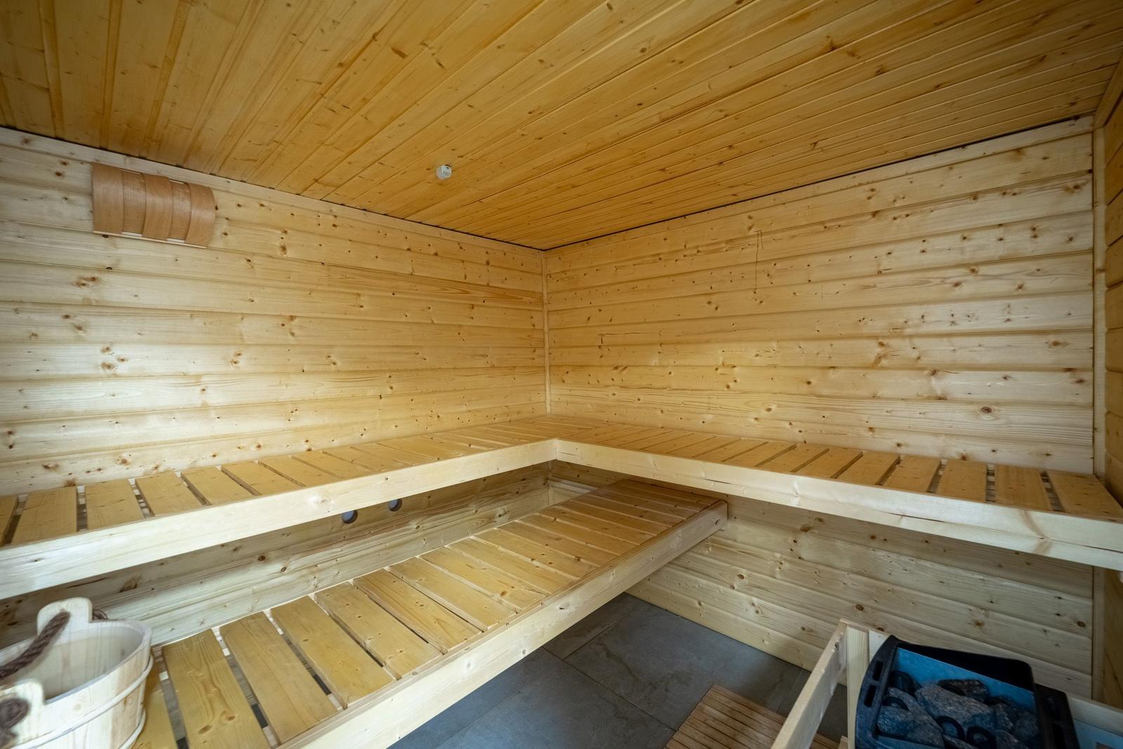 Holzsauna mit mehreren Sitzbänken und einem Eimer.