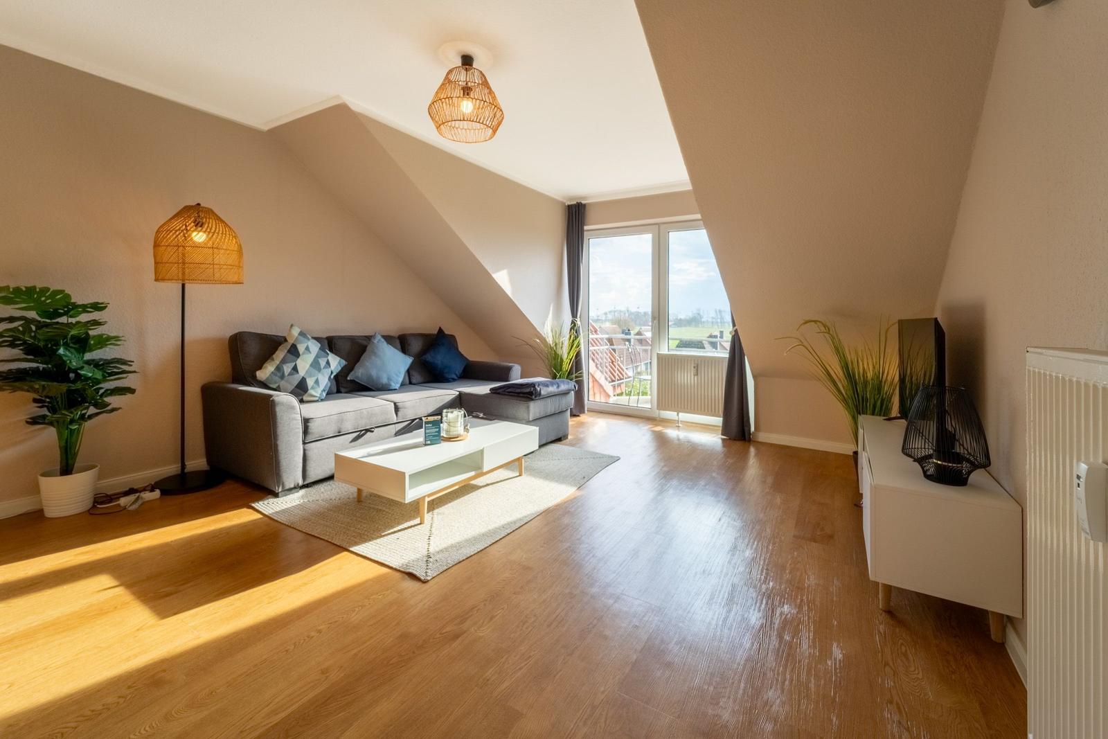 Wohnzimmer mit Sofa, Couchtisch und Blick auf Balkon