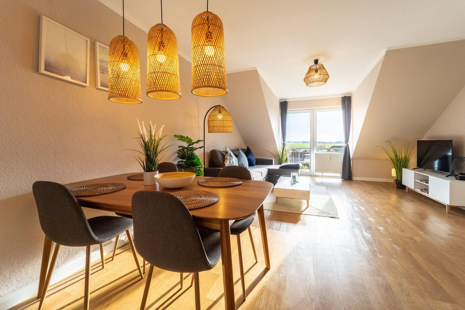 Wohn- und Essbereich mit Holzboden, Esstisch, Sofa und Fernseher.