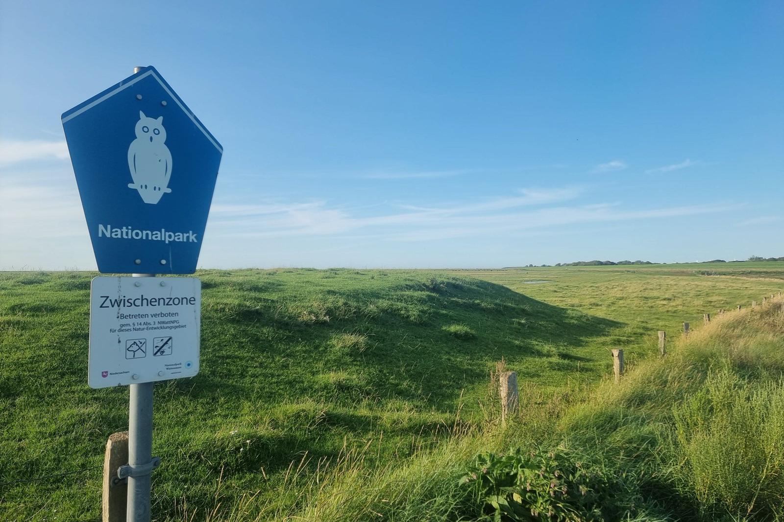 Nationalpark-Zeichen weist auf Schutzzone hin. Grünland und Himmel im Hintergrund.
