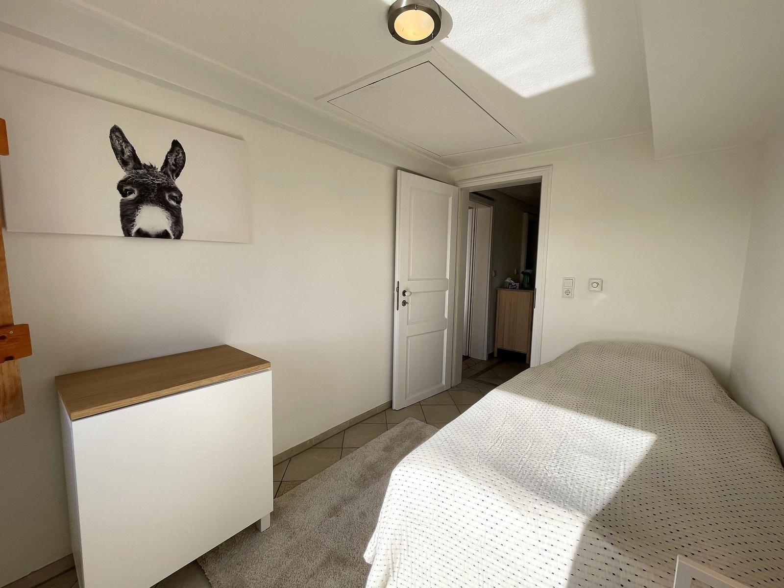 Bedroom with bed, cabinet, and wall art of a donkey.
