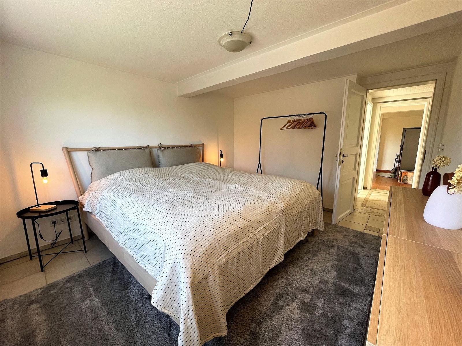 Bedroom with bed, clothing rack, and nightstand.