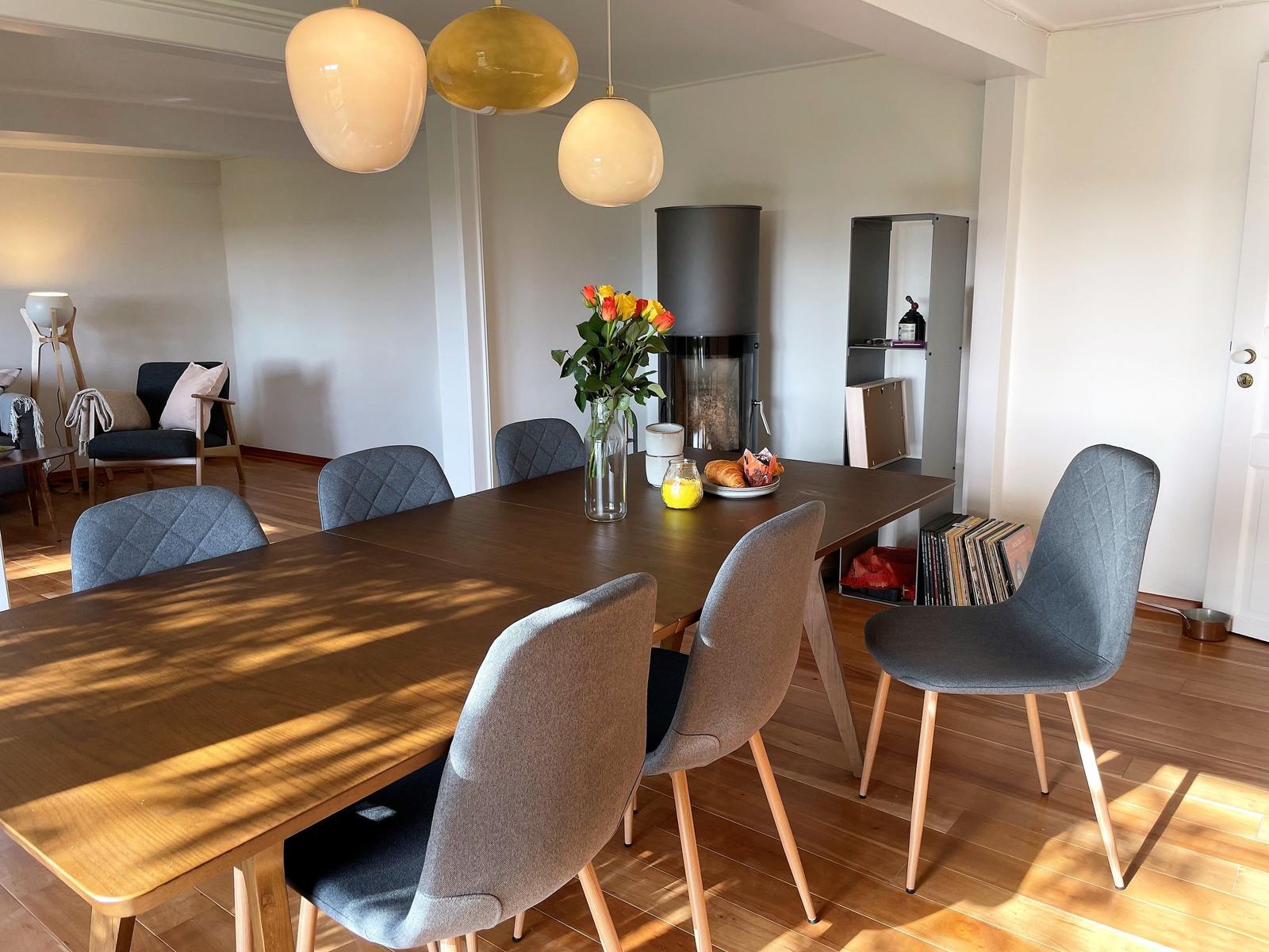 Dining area with wooden table, gray chairs, and three pendant lights.