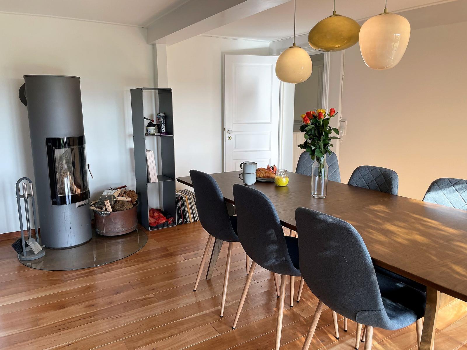 Dining room with table, chairs, fireplace, and pendant lamps.