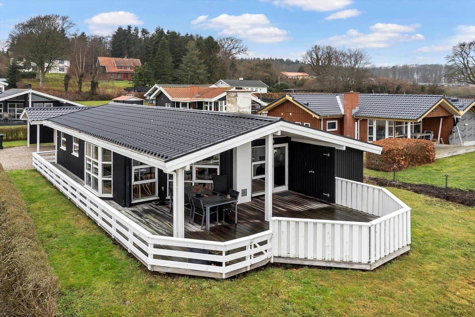 Schwarzes Haus mit weißer Veranda und Garten