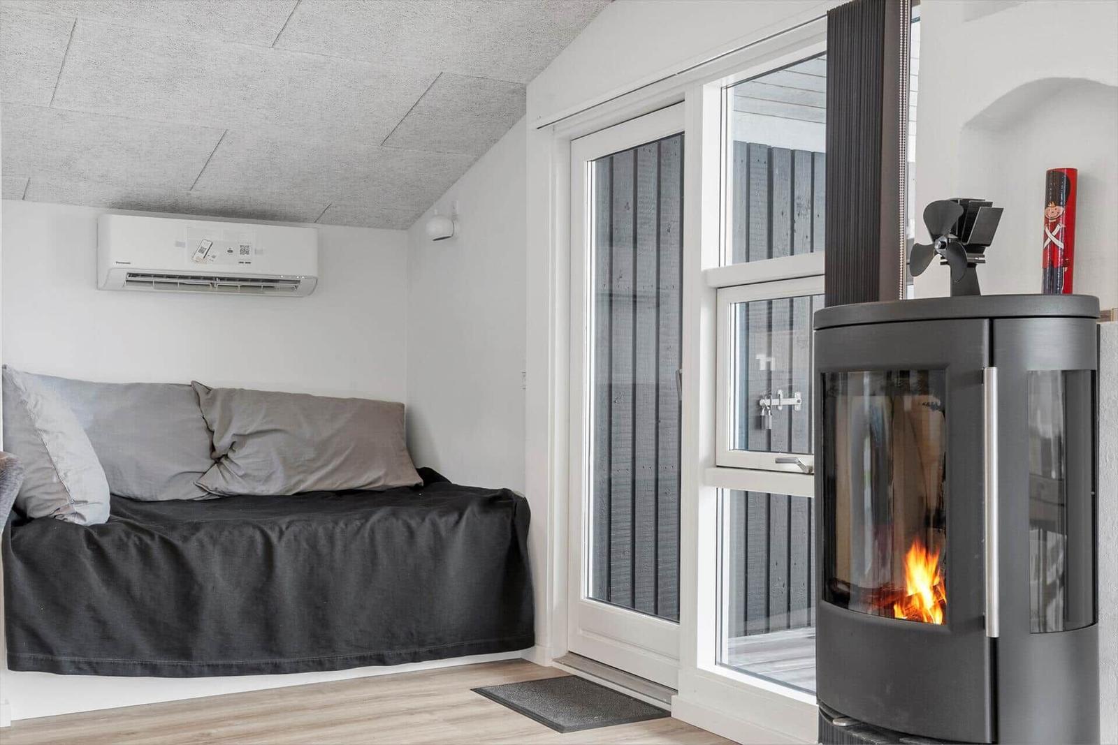 Schlafzimmer mit Bett, Kaminofen und Glastür.